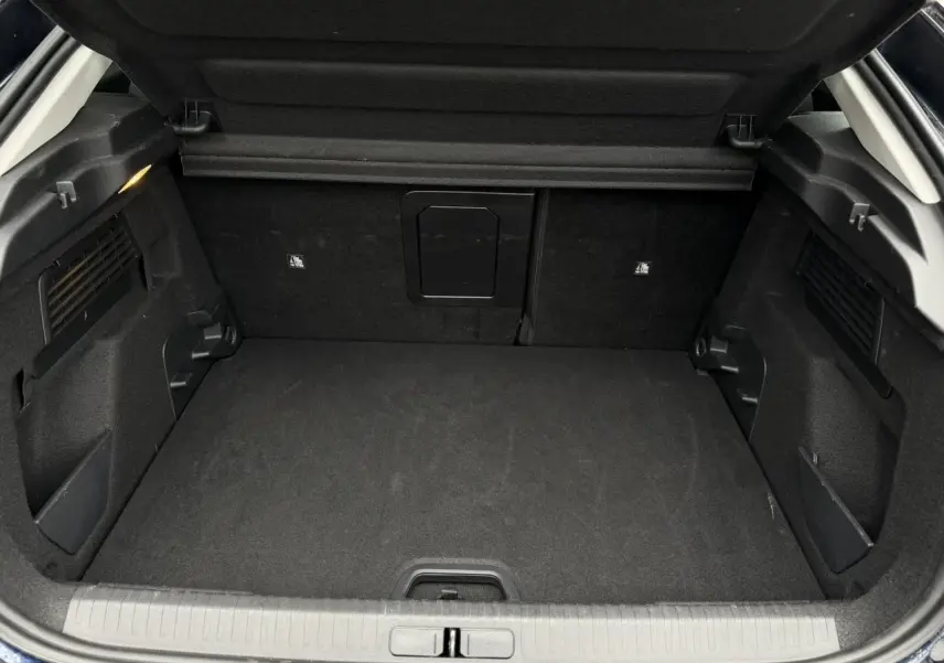 Coffre ouvert vu de l'arrière du Citroën C4 2024 Bleu Eclipse avec intérieur noir et trappe à skis centrale.
