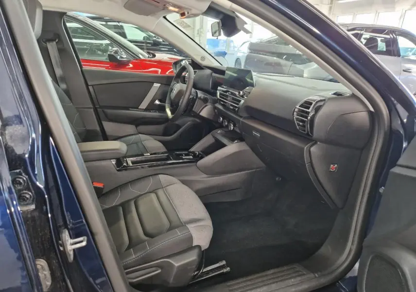 Intérieur avant droit de Citroën C4 2024 bleu Eclipse, sièges tissu gris et noir avec accoudoir central.