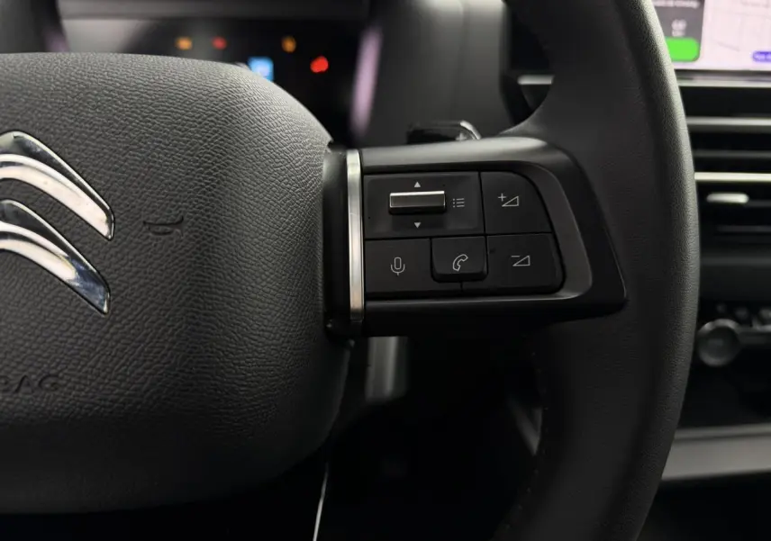 Gros plan sur le côté droit du volant noir de la Citroën C4 2024 avec commandes audio et téléphone intégrées.
