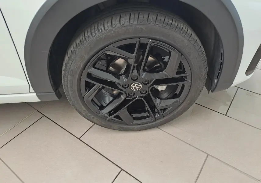 Gros plan sur la jante noire en alliage 18 pouces York du côté gauche d’un Volkswagen Taigo blanc toit noir.