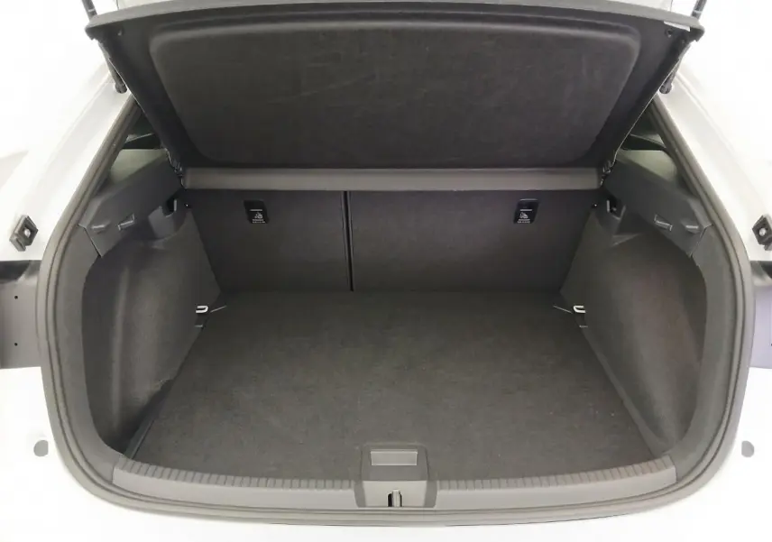 Coffre ouvert vu de face d'un Volkswagen Taigo blanc pur, intérieur noir avec cache-bagages relevé.
