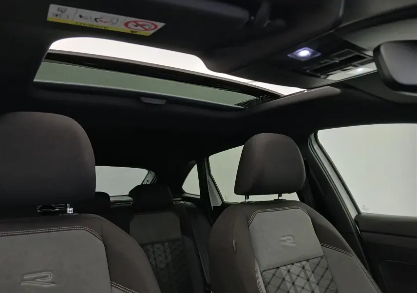 Vue intérieure du Volkswagen Taigo R-Line 2025, sièges noirs avec logo R et toit ouvrant en verre ouvert.