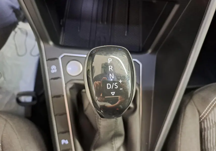 Gros plan sur le levier de vitesses noir brillant de la Volkswagen Taigo 1.5 TSI R-Line, intérieur gris et console noire.