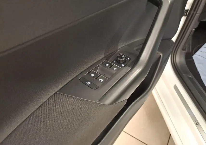 Vue rapprochée de la porte avant gauche du Volkswagen Taigo blanc, avec commandes électriques des vitres et rétroviseurs noirs.
