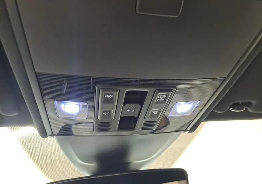 Vue intérieure du panneau de commandes du toit ouvrant et des éclairages avant allumés sur un Volkswagen Taigo blanc toit noir.