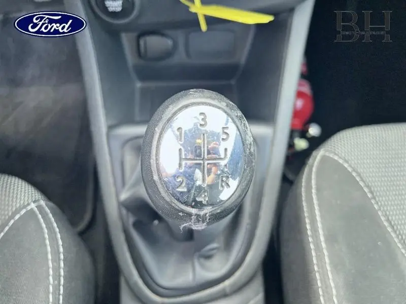 Gros plan sur le levier de vitesses manuel de la Renault Clio gris Cassiopée, entouré des sièges avant en tissu gris.