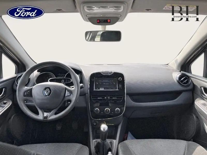 Vue intérieure avant du tableau de bord et volant cuir d’une Renault Clio gris Cassiopée avec écran tactile et boîte manuelle.