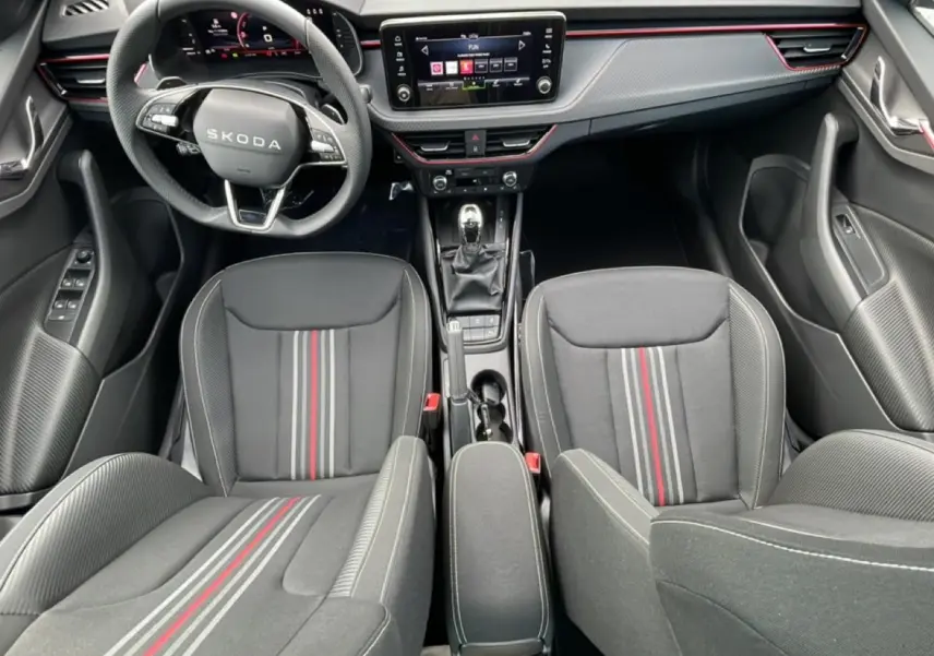 Vue intérieure frontale du Skoda Kamiq Monte Carlo 2026, sièges sport noirs avec bandes rouges et tableau de bord moderne.