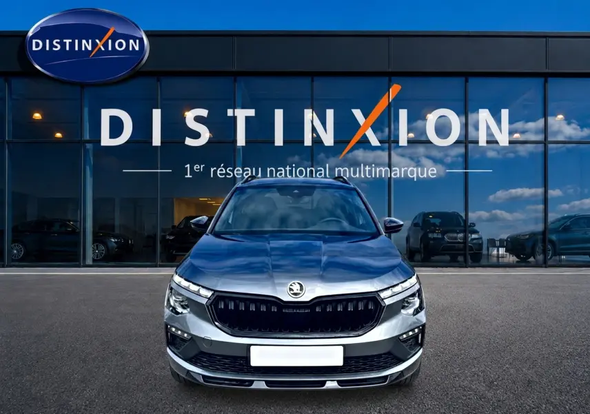 Vue frontale d'un Skoda Kamiq gris graphite 2026 avec calandre noire et phares LED devant un showroom Distinxion.