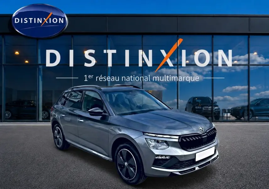 Vue 3/4 avant droite d'un Skoda Kamiq gris graphite avec jantes alu noires et toit panoramique en verre.