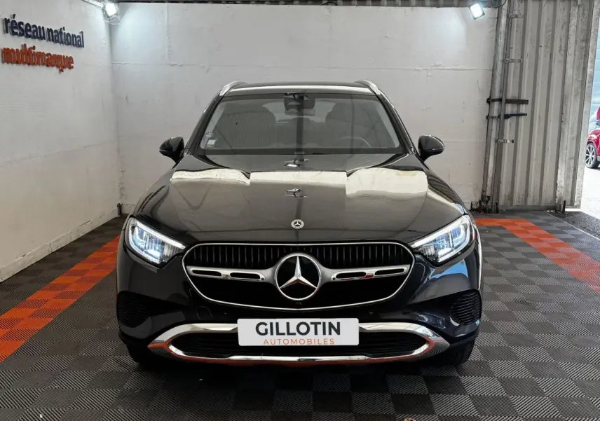 Vue frontale d'un Mercedes GLC 300 E Business Line 4MATIC gris foncé avec calandre chromée et phares LED allumés.
