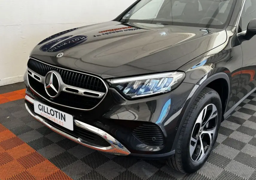 Vue 3/4 avant droit d'un Mercedes GLC 300 E Business Line hybride rechargeable gris foncé avec calandre chromée et phares LED.