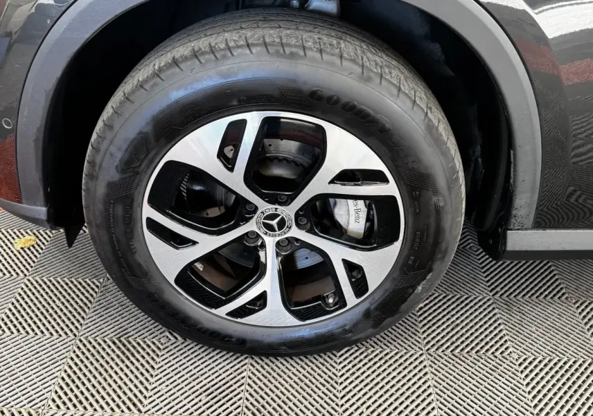 Gros plan sur la roue avant droite d’un Mercedes GLC gris foncé avec jante alliage bicolore et logo central étoile.