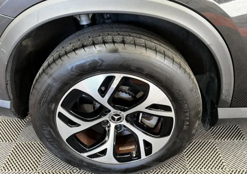 Gros plan sur la roue avant droite d’un Mercedes GLC gris foncé avec jante alliage bicolore et pneu Goodyear.