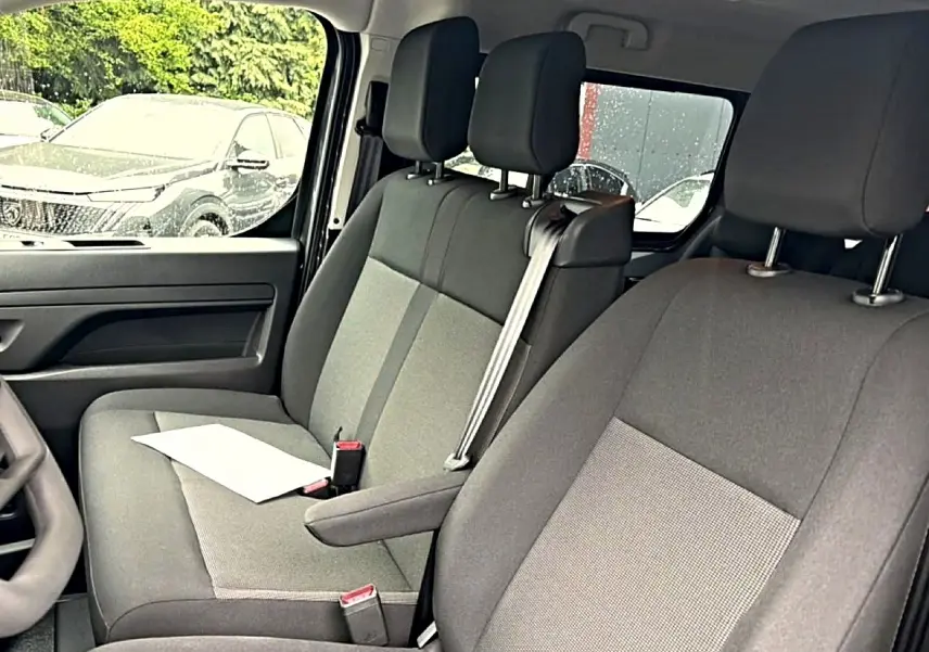 Vue intérieure côté conducteur du Fiat Scudo Combi 2026, sièges bi-ton gris avec accoudoir central et ceinture de sécurité.