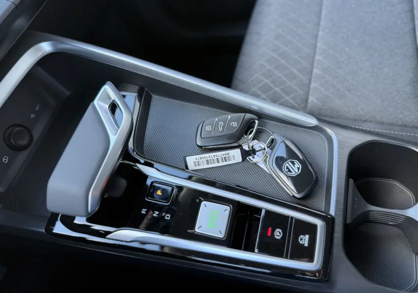 Gros plan sur la console centrale du MG ZS Hybrid 2026, avec levier de vitesse automatique et clés posées sur surface noire texturée.