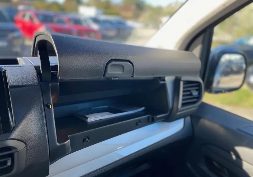 Intérieur du Peugeot Expert Fourgon 2026, vue sur la boîte à gants ouverte côté passager avec tableau de bord gris et noir.