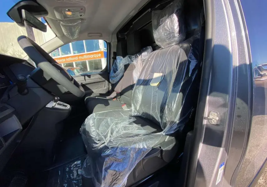 Vue intérieure côté conducteur du Peugeot Expert Fourgon gris Artense, sièges avant protégés par film plastique.