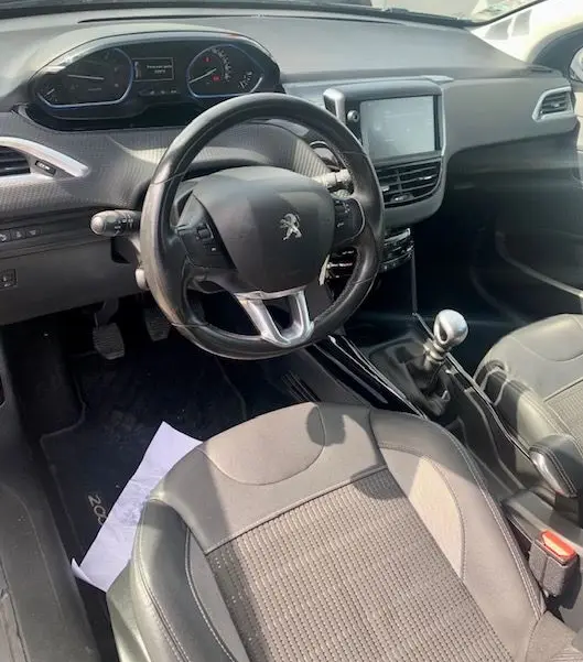 Intérieur du Peugeot 2008 2015 gris, vue côté conducteur montrant volant, tableau de bord et levier de vitesses manuel.