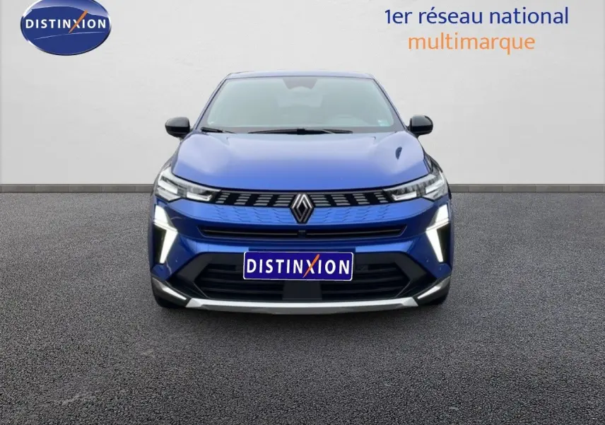 Vue frontale d'une Renault Symbioz bleu iron metal avec feux LED allumés sur un sol goudronné.
