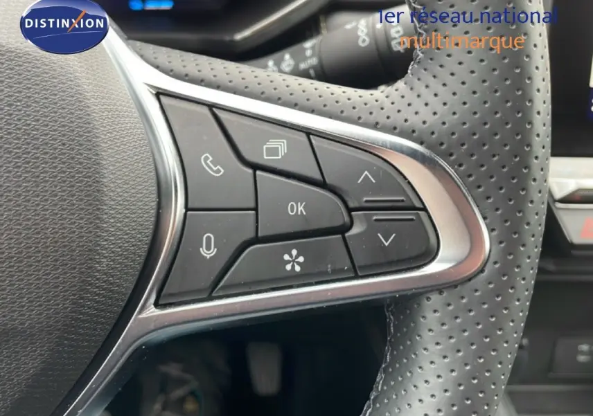Gros plan sur les commandes multifonctions à gauche du volant perforé du Renault Symbioz bleu iron metal, version hybride 2025.