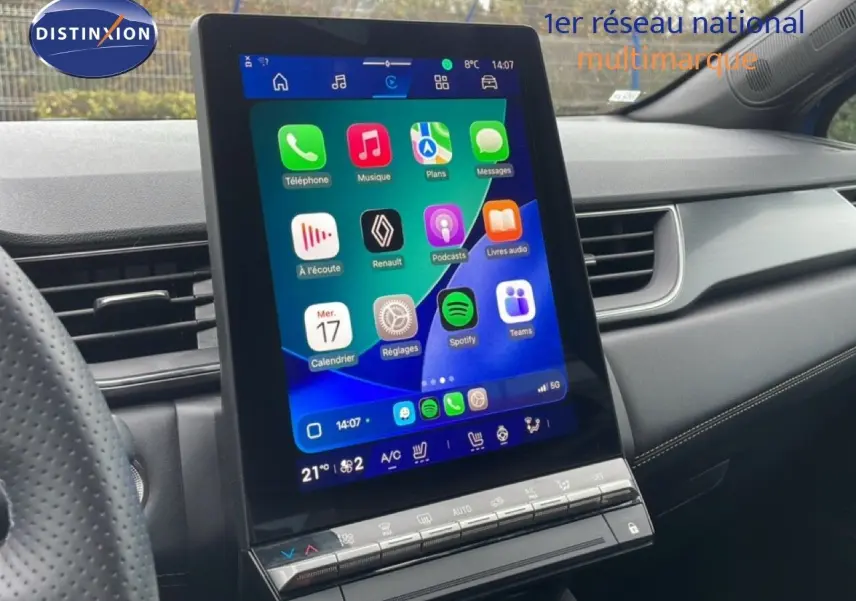 Vue intérieure centrée sur l'écran tactile vertical du tableau de bord d'une Renault Symbioz bleu iron metal, avec commandes climatisation visibles.