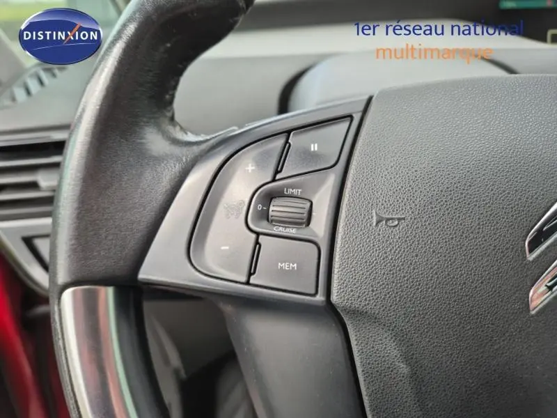Gros plan sur le volant cuir noir du Citroën Grand C4 Spacetourer rouge, avec commandes intégrées au volant.
