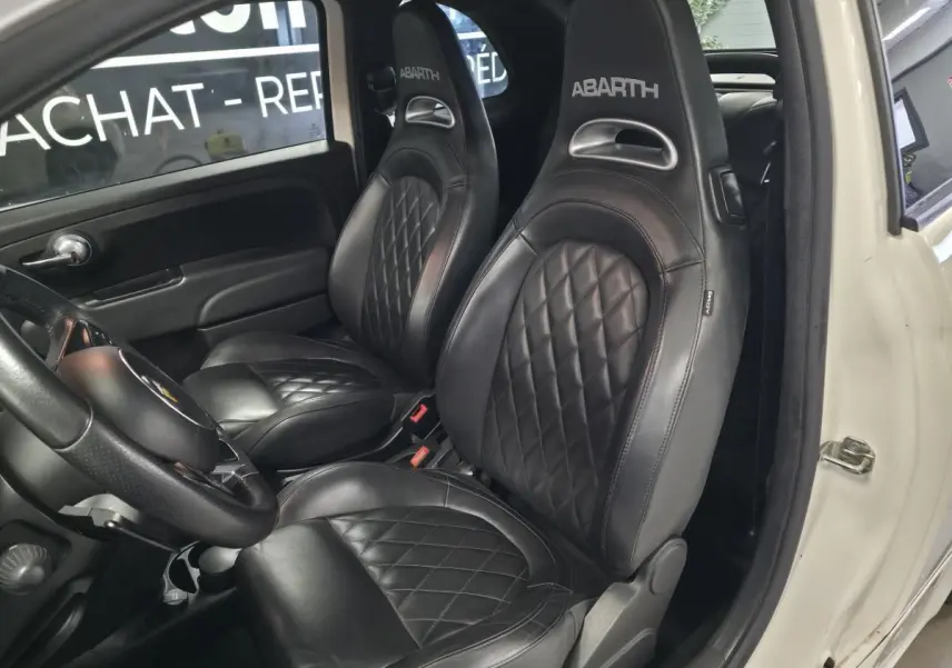 Vue intérieure côté gauche montrant les sièges sport noirs en cuir avec logo ABARTH sur une Abarth 595C blanche.