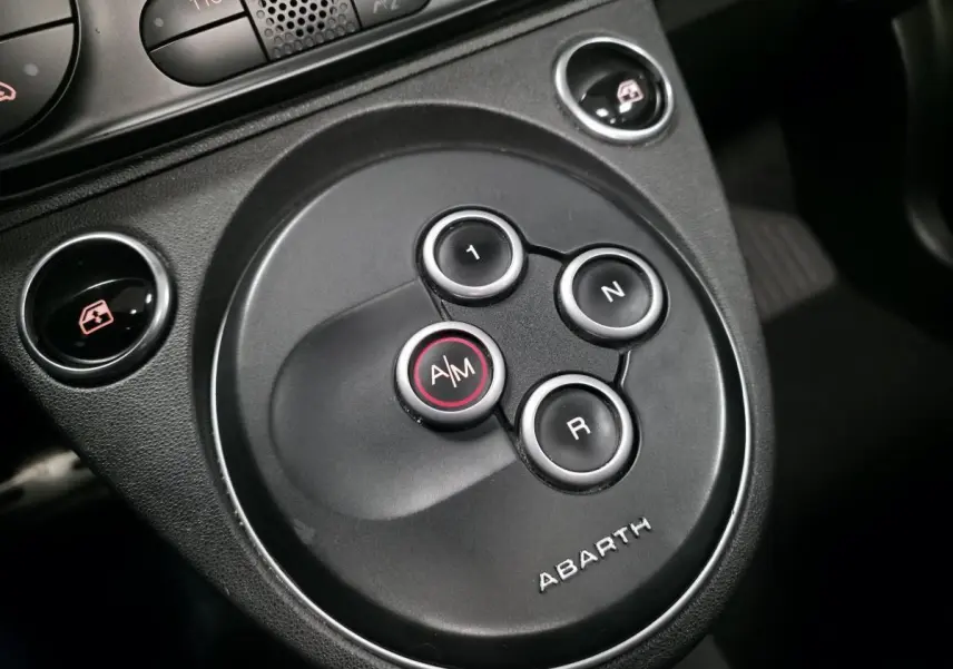 Gros plan sur la commande de lève-vitre et le bouton TTC sur la console centrale noire de l'Abarth 500 blanc.