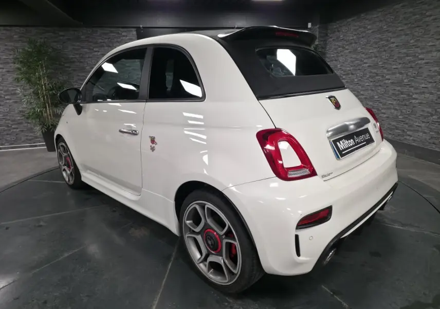 Vue 3/4 arrière droite de l'Abarth 595C Turismo blanc avec étriers de frein rouges et toit noir ouvrant.