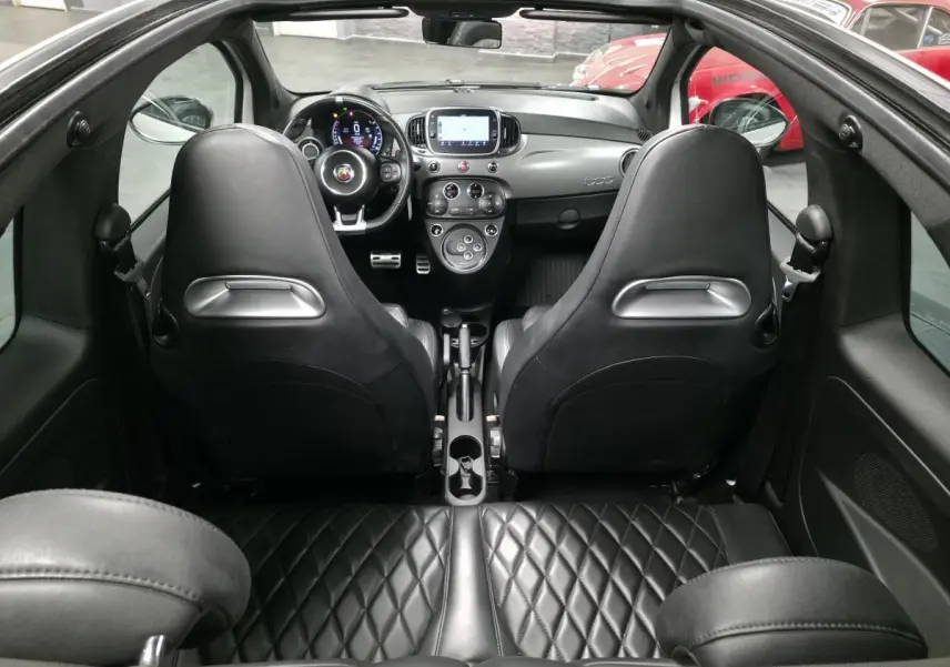 Vue intérieure arrière de l'Abarth 595C Turismo 2021, sellerie cuir noire matelassée et tableau de bord gris satiné.