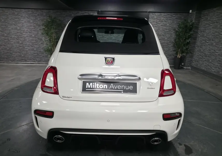 Vue arrière d'une ABARTH 500 blanche avec double sortie d'échappement chromée et toit noir en toile.