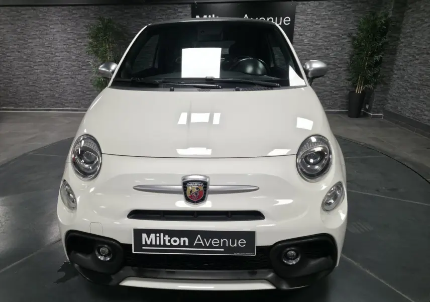Vue frontale d'une Abarth 500 blanche avec calandre nid d'abeille et logo Abarth visible au centre.