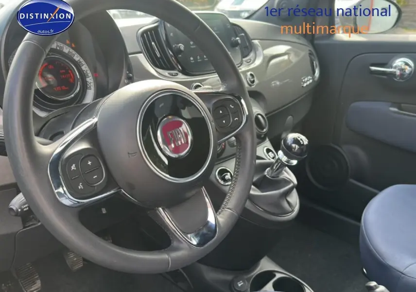 Vue intérieure côté conducteur du tableau de bord gris et volant cuir noir d'une Fiat 500 1.0 70 bsg cult avec boîte manuelle.