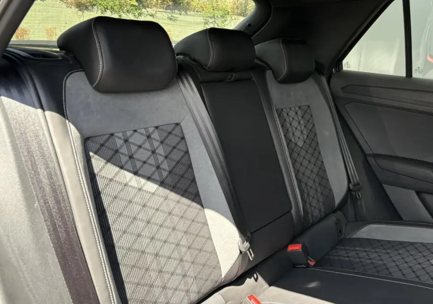Vue intérieure arrière du Volkswagen T-Roc 1.5 TSI R-Line 2025, sièges cuir et alcantara gris avec surpiqûres blanches.