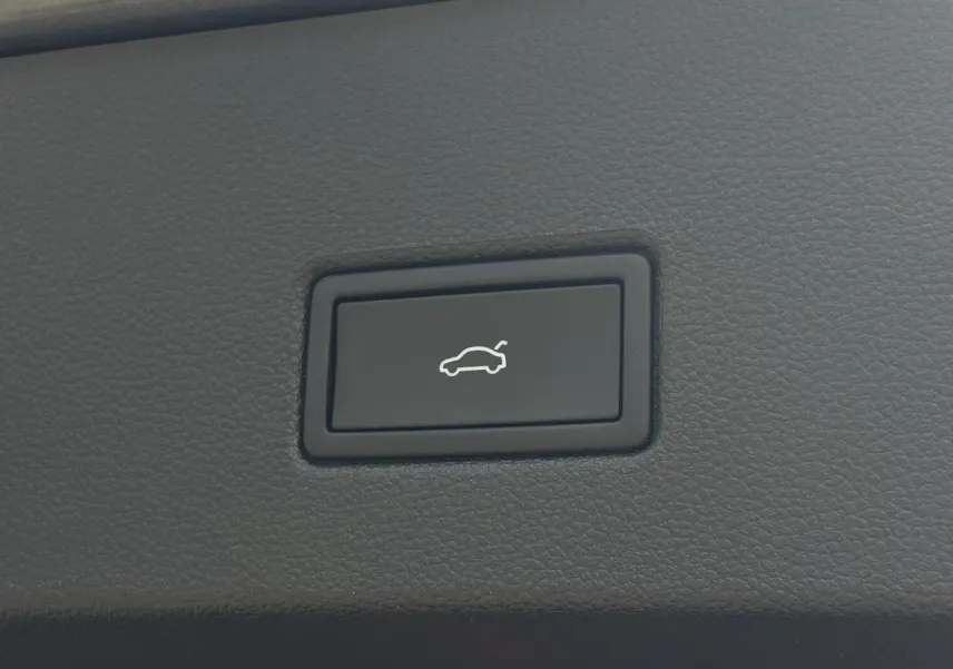 Bouton noir d'ouverture électrique du hayon sur tableau de bord en cuir gris du Volkswagen T-Roc 2025.