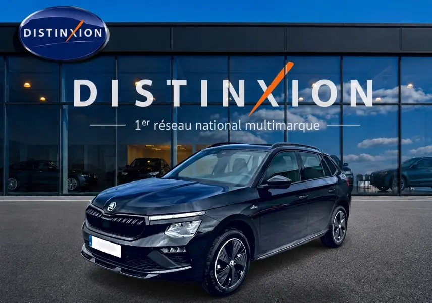 Vue 3/4 avant gauche d’un Skoda Kamiq noir Monte Carlo avec jantes alu distinctives, devant une vitrine Distinxion.