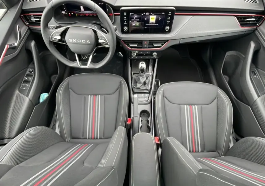 Vue intérieure frontale du Skoda Kamiq Monte Carlo 2026, sièges sport noirs avec bandes rouges et tableau de bord moderne.