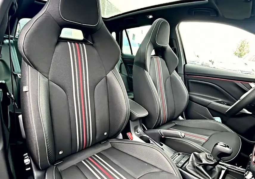 Intérieur avant du Skoda Kamiq Monte Carlo 2026, sièges sport noirs avec bandes rouges et toit panoramique en verre.