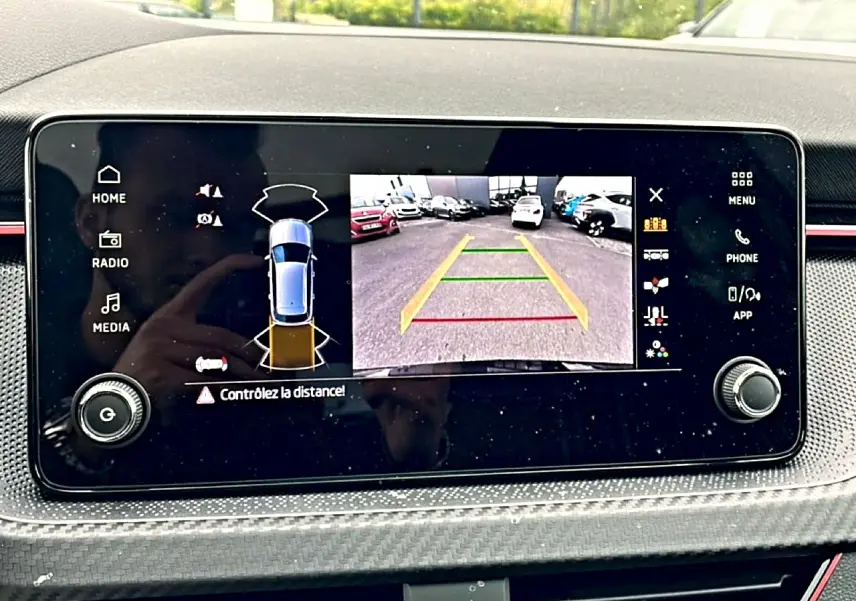 Écran tactile intérieur montrant la caméra de recul et l’aide au stationnement du Skoda Kamiq noir, vue de face.