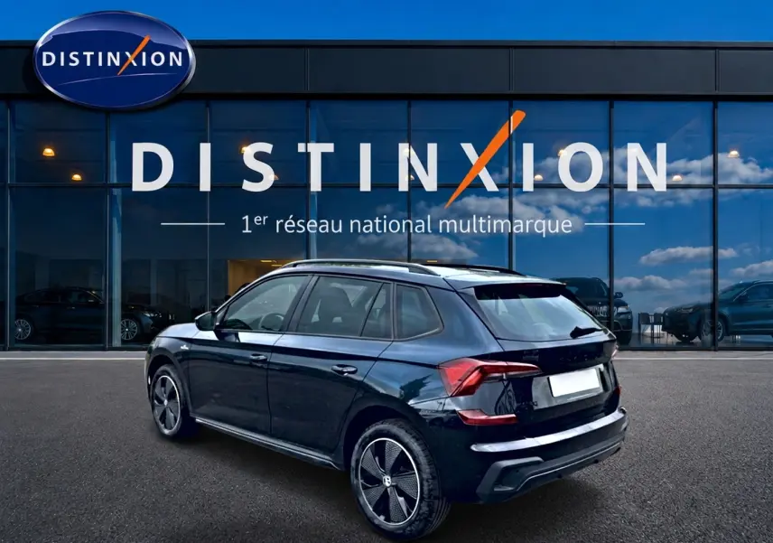 Vue 3/4 arrière droite d'un Skoda Kamiq noir avec jantes alu, garé devant une vitrine Distinxion.