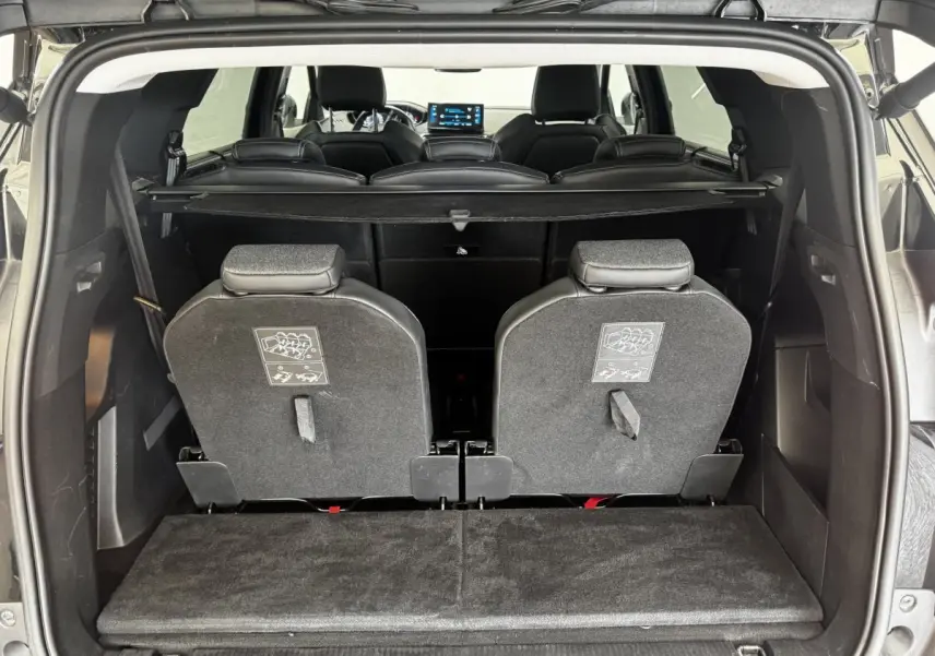 Vue arrière du coffre ouvert d’un Peugeot 5008 noir 2022, montrant la 3ème rangée de sièges individuels rabattus.