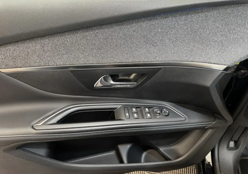 Vue rapprochée de la porte côté conducteur du Peugeot 5008 noir, avec commandes de vitres et poignée argentée.
