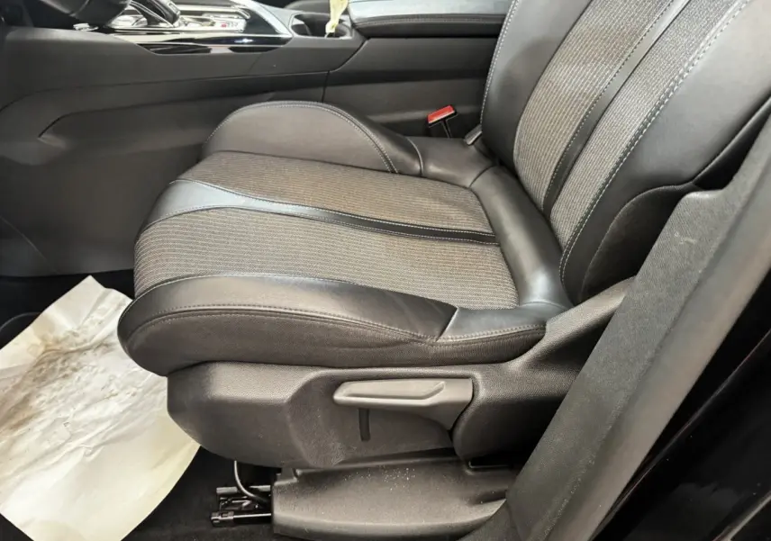 Gros plan sur le siège avant droit en cuir et tissu gris du Peugeot 5008 noir, avec levier de réglage manuel visible.