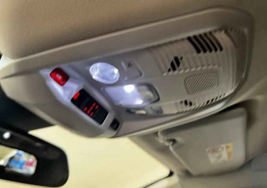 Plafonnier intérieur avec éclairage LED et bouton d'appel d'urgence dans un Peugeot 5008 noir, vue vers le toit côté conducteur.