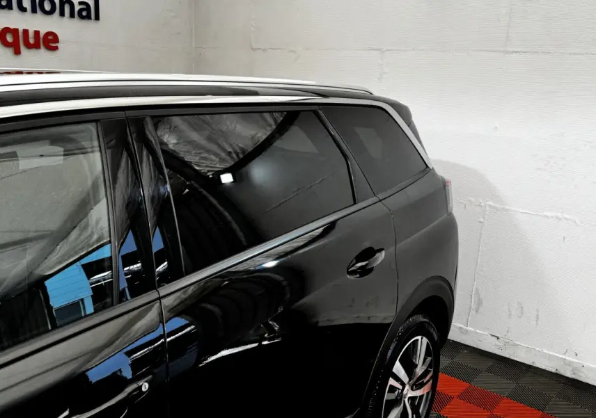 Vue côté droit arrière d’un Peugeot 5008 noir, mettant en valeur les vitres teintées et les jantes alliage modernes.