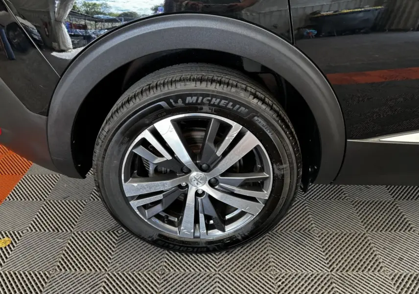 Gros plan sur la roue arrière droite d’un Peugeot 5008 noir, avec jante alliage et pneu Michelin.