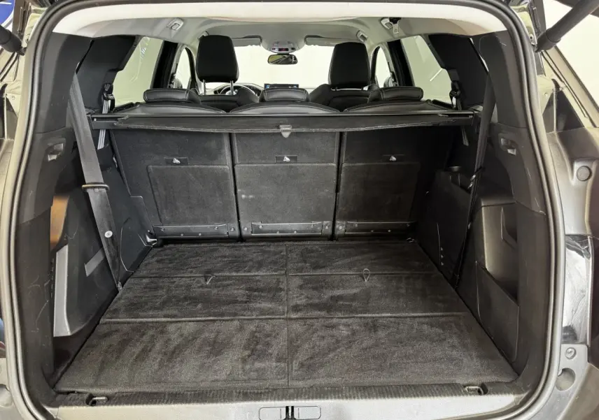 Coffre ouvert vu de l'arrière d'un Peugeot 5008 noir, avec sièges rabattus et plancher plat.