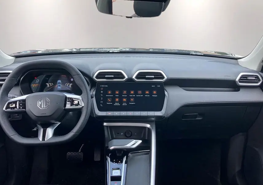 Vue intérieure frontale du tableau de bord noir du MG ZS 1.5 hybrid 197 luxury avec écran tactile central et volant multifonction.