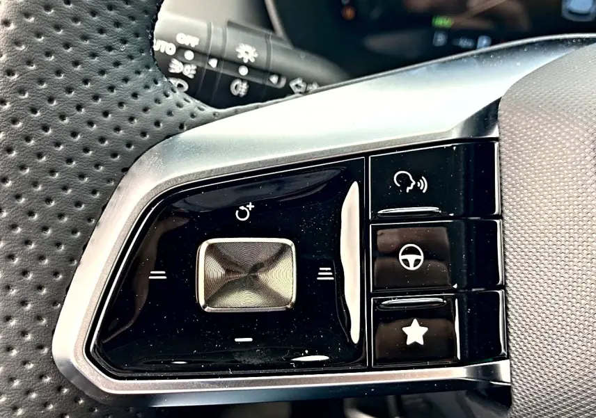 Gros plan sur les commandes noires et argentées du volant multifonction perforé côté gauche du MG ZS 1.5 hybrid 197 luxury noir.